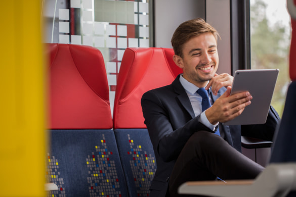 a man sits on a shuttle bus with his tablet