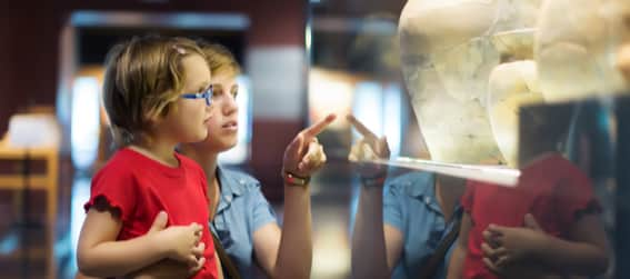 A woman and child looking at a museum pottery exhibit.